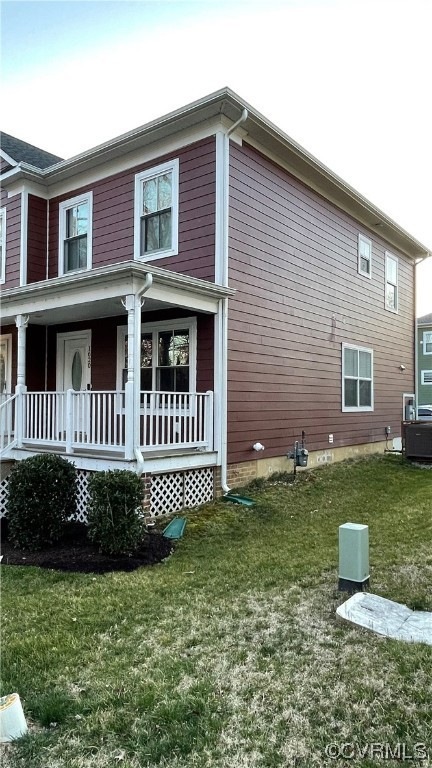 Back of house with a yard and covered porch