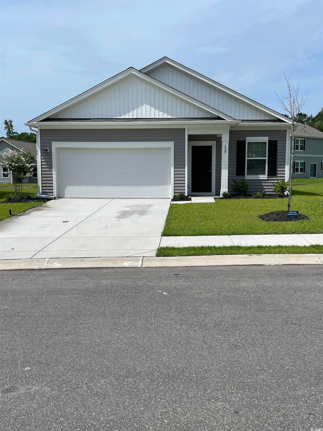 Ranch-style house with a garage, a front yard, driveway, and board and batten siding