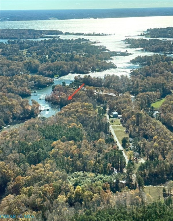 Aerial overview of property's location with a nearby body of water and a heavily wooded area