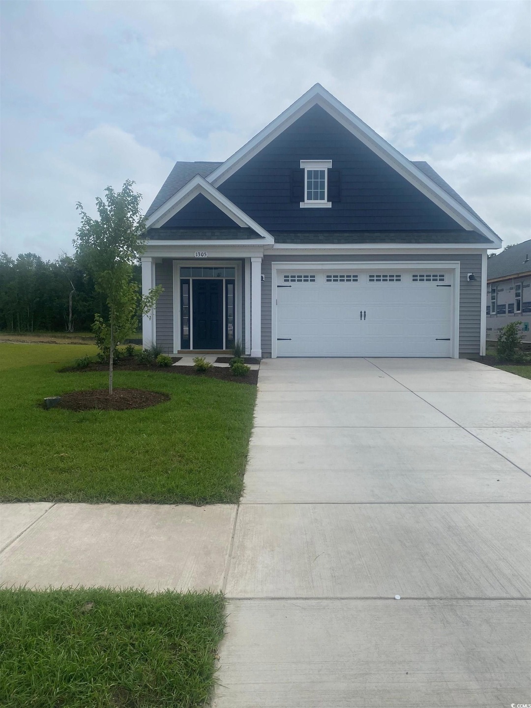 View of front facade featuring driveway, a front yard, and an attached garage