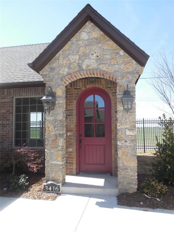 Doorway to property featuring brick siding, roof with shingles, and stone siding