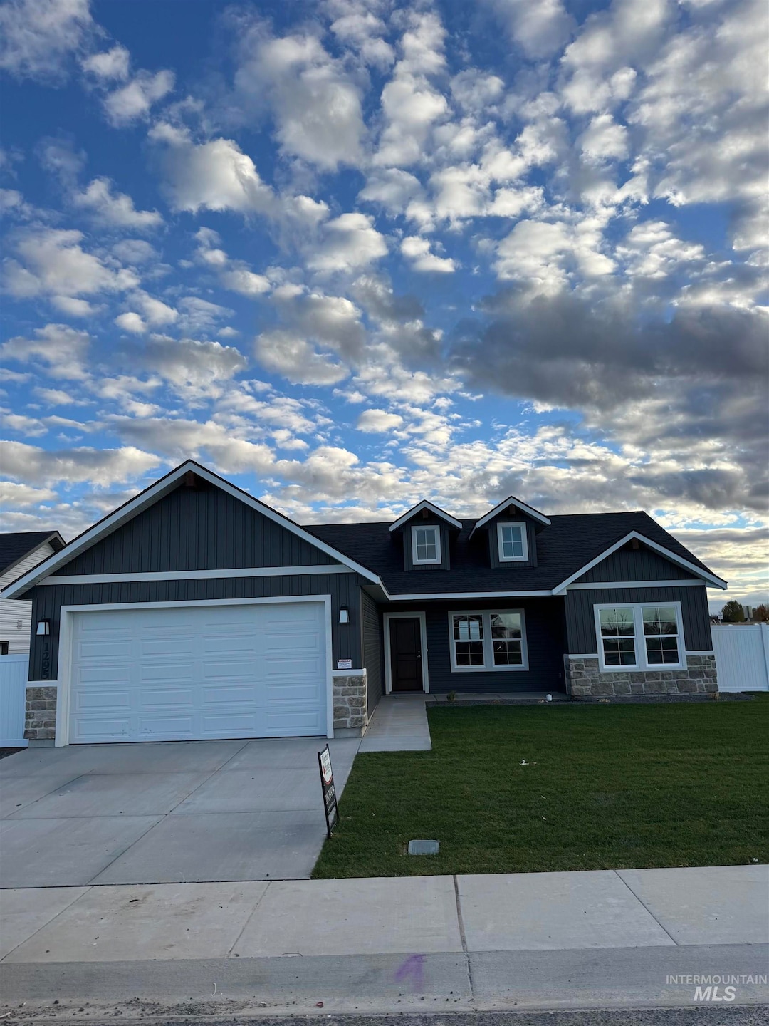 Craftsman-style house with stone siding, driveway, an attached garage, and board and batten siding