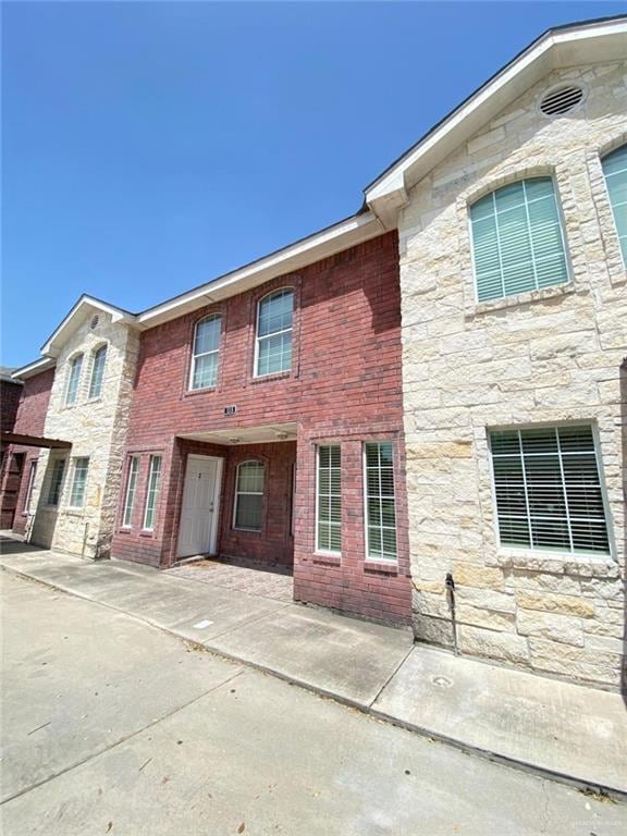 View of front facade featuring a patio area and stone siding