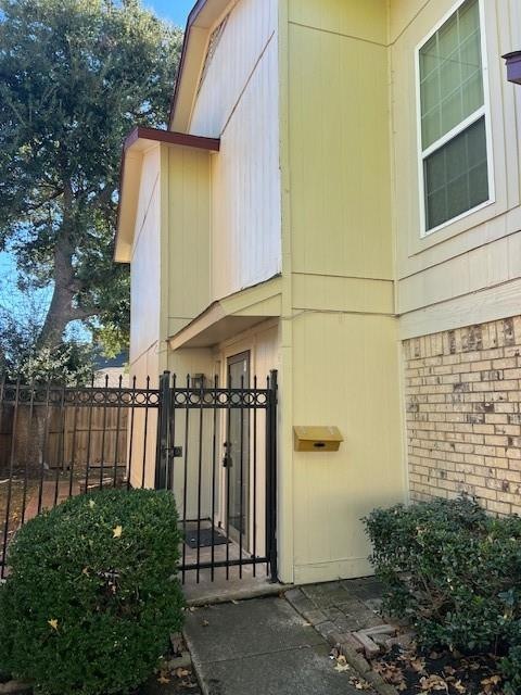 Property entrance with a gate, brick siding, and f