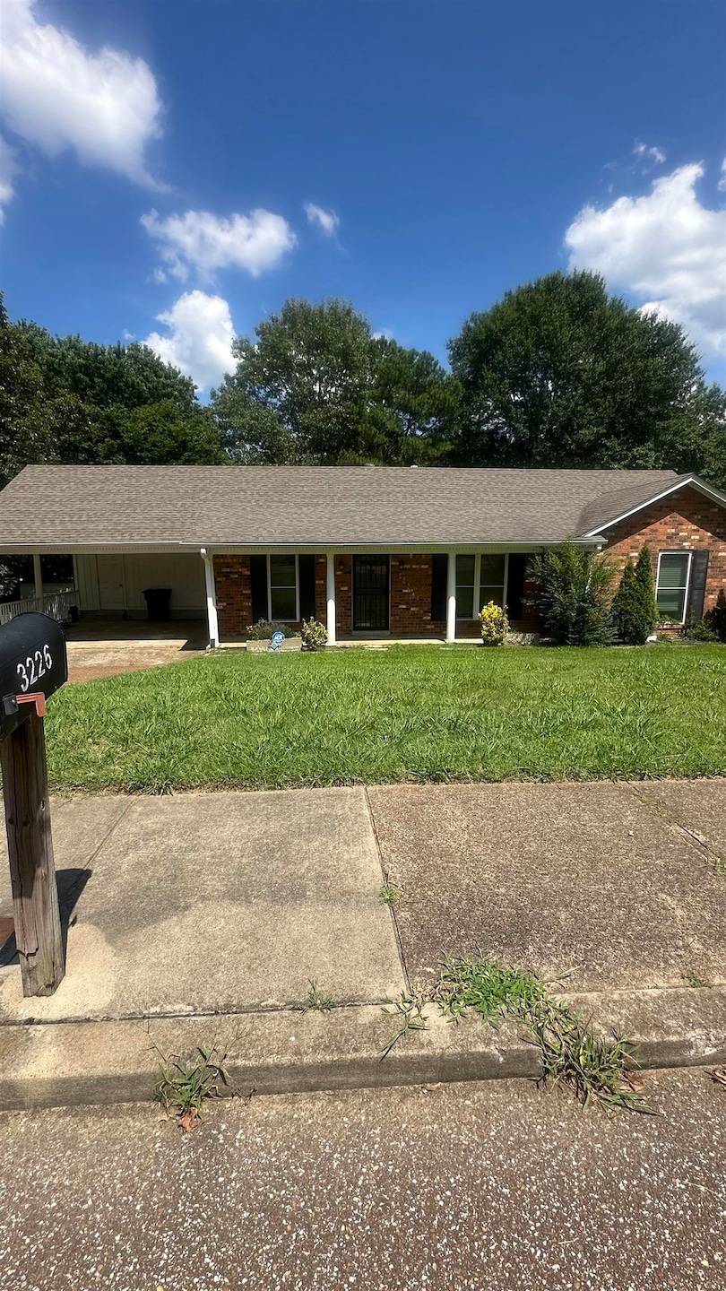 Single story home with a front yard, driveway, an attached carport, and roof with shingles