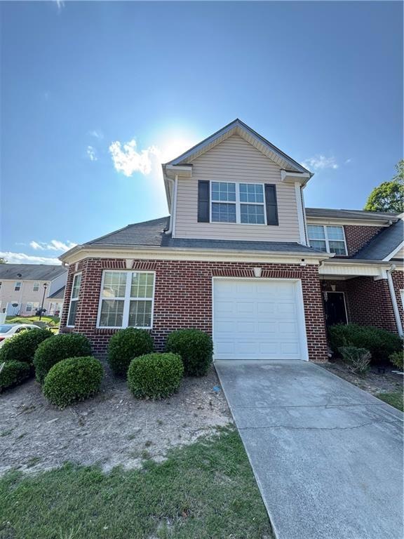 View of front of property featuring brick siding, an attached garage, and driveway