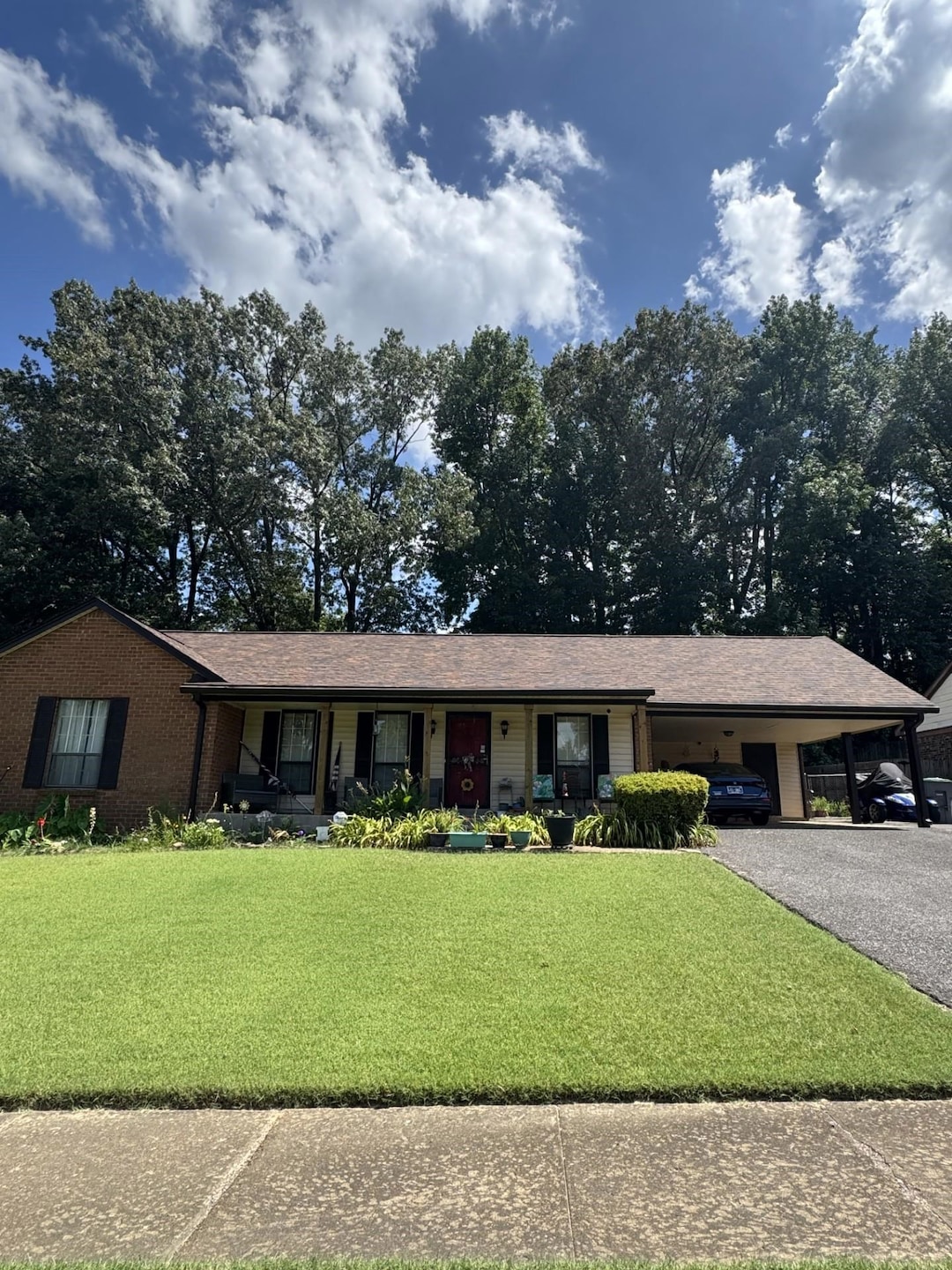 Single story home with an attached carport, a front yard, driveway, and a porch