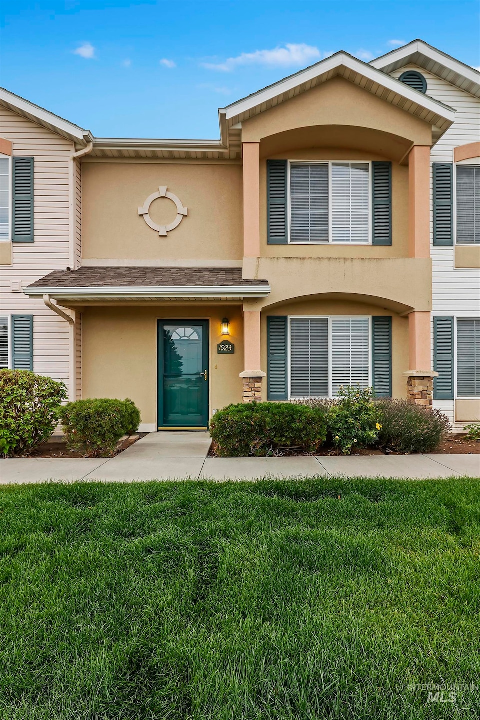 Townhome / multi-family property with stucco siding and a front lawn