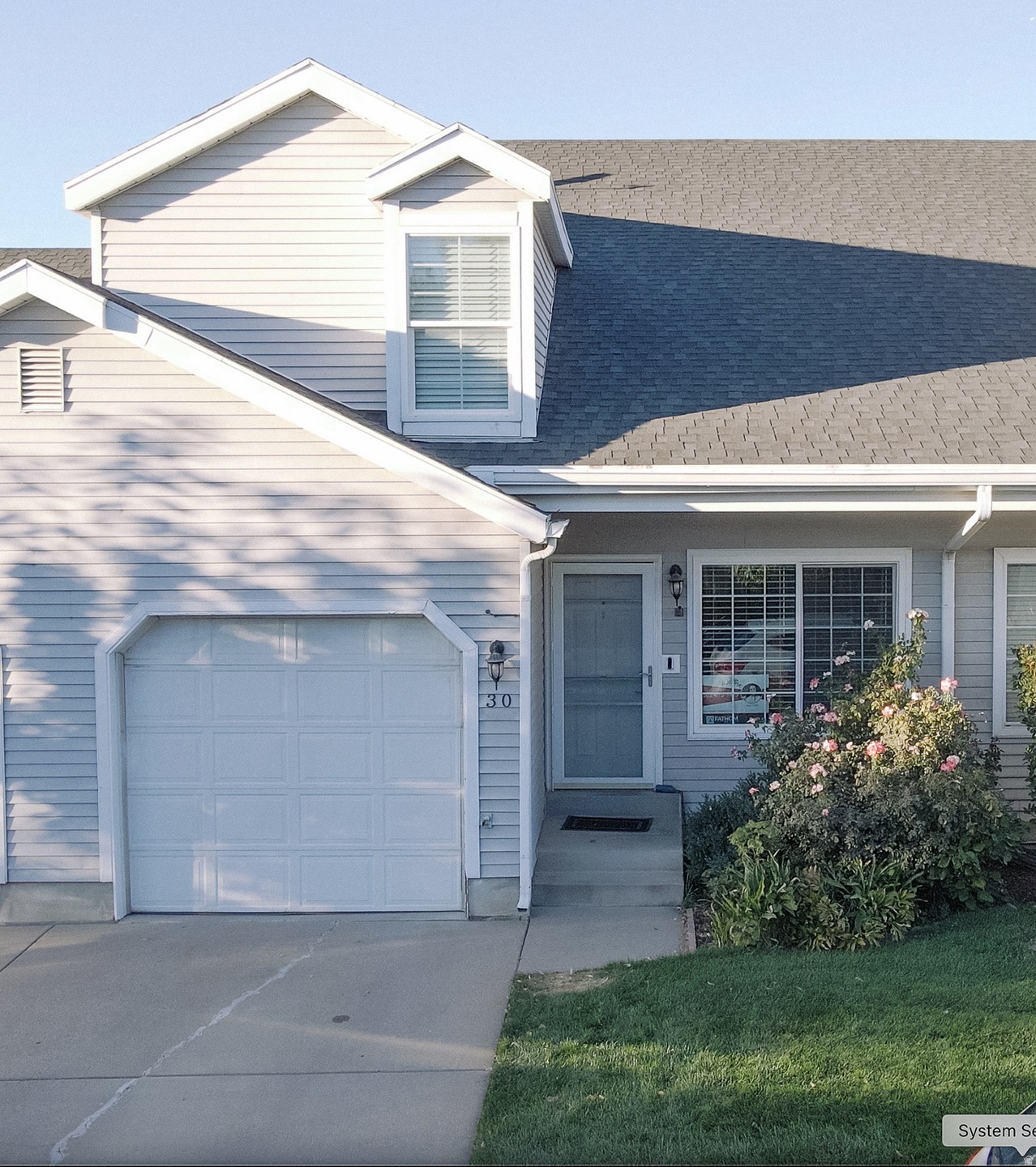 View of front of property with a garage, driveway, and a shingled roof