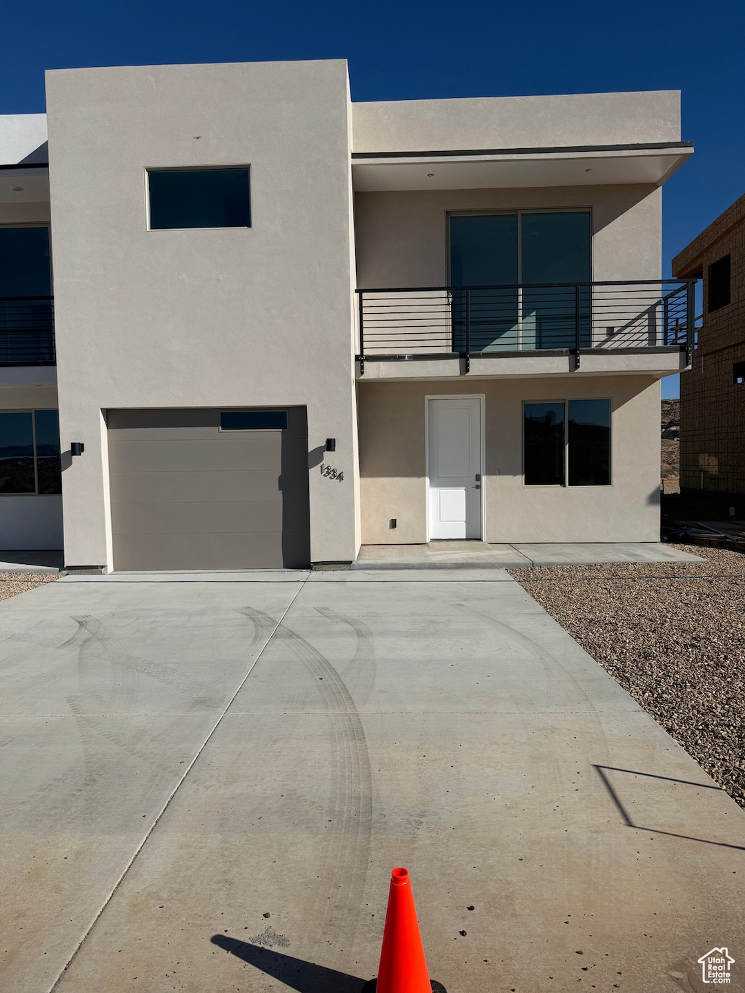 Contemporary home featuring stucco siding, a balcony, an attached garage, and concrete driveway