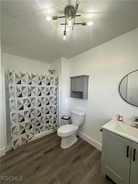 Full bath with vanity, dark wood-style floors, tiled shower, and a textured ceiling