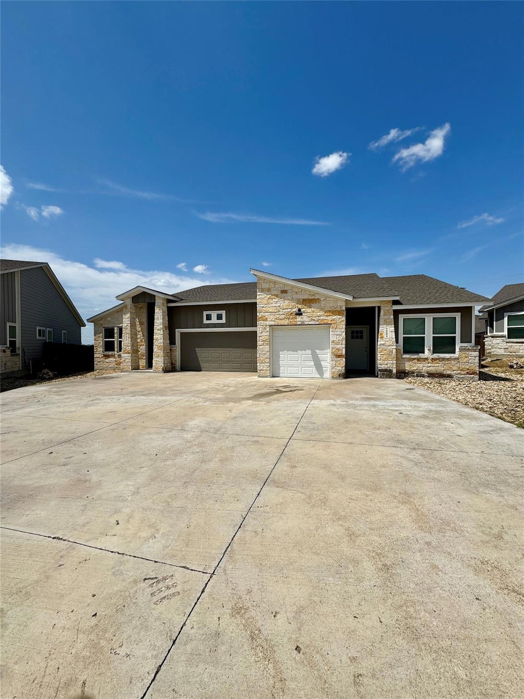 Prairie-style house featuring stone siding, concrete driveway, an attached garage, and a shingled roof