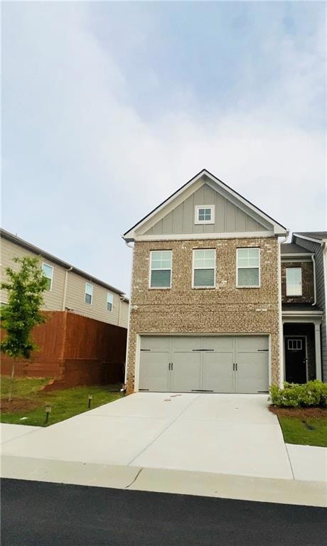 View of front facade with board and batten siding, driveway, and an attached garage