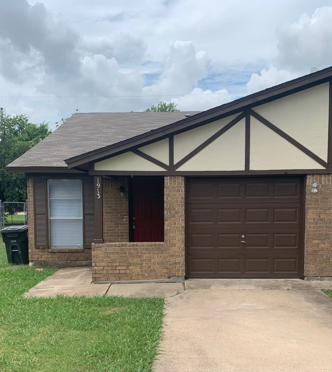 Ranch-style home featuring brick siding, a shingled roof, driveway, a front yard, and a garage