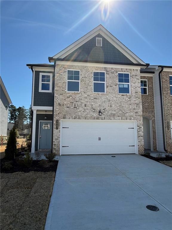 View of front of property with an attached garage, concrete driveway, and brick siding