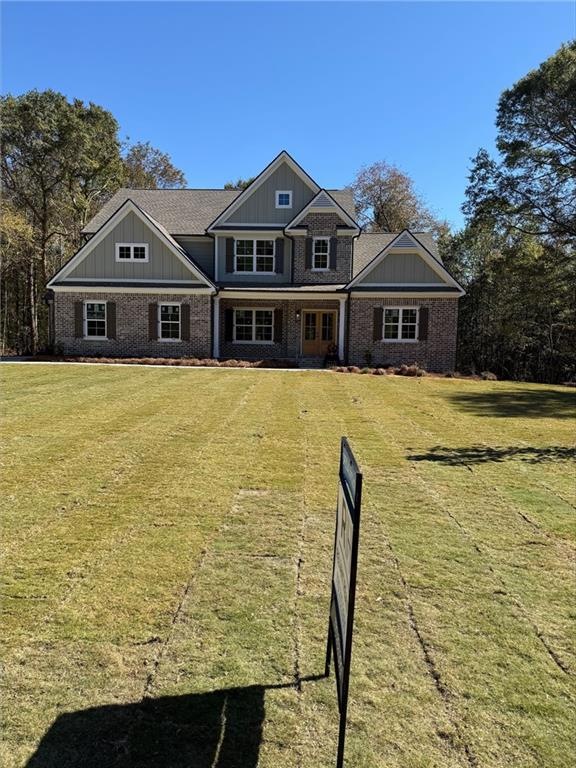 Craftsman-style house with board and batten siding, a front yard, a porch, and brick siding