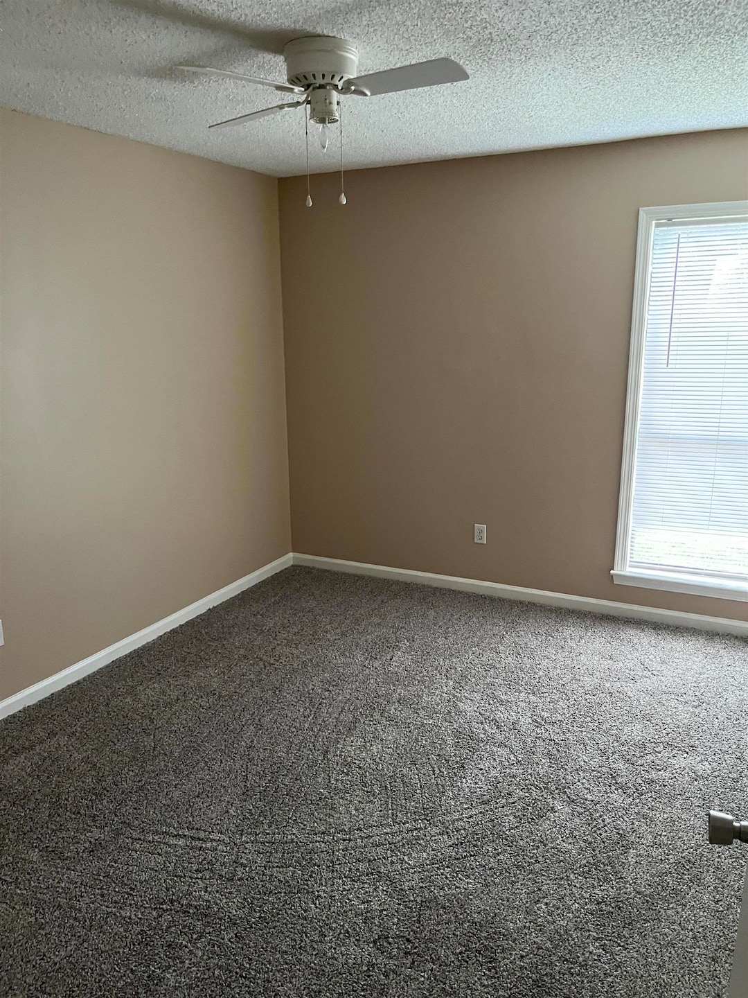 Empty room featuring ceiling fan, a textured ceili