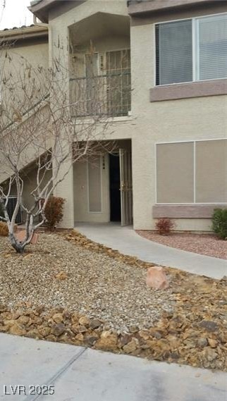 View of front of home featuring a balcony and stucco siding