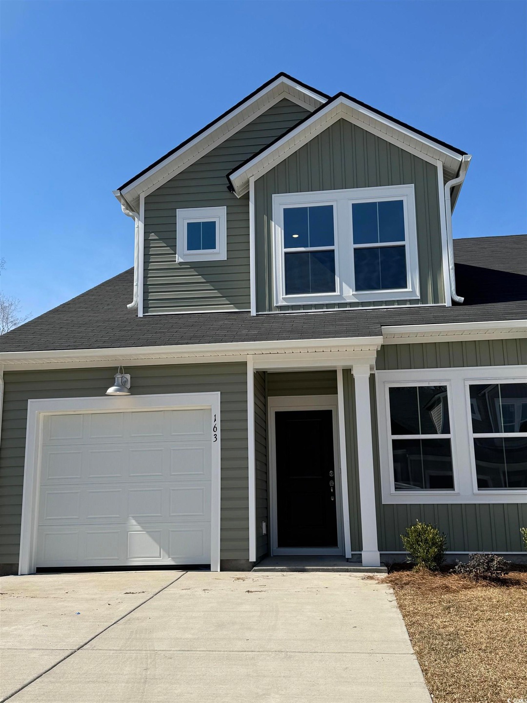 View of front of property featuring driveway, board and batten siding, and roof with shingles