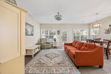 Living area with light wood finished floors, a textured ceiling, and a chandelier