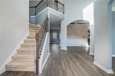 Staircase with baseboards, arched walkways, a high