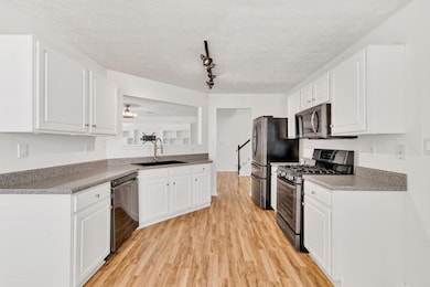 Bright and functional kitchen featuring ample white cabinetry, sleek dark countertops, and modern black appliances including a gas range and built-in microwave