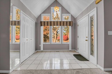 Entrance foyer featuring light tile patterned flooring, a chandelier, and lofted ceiling