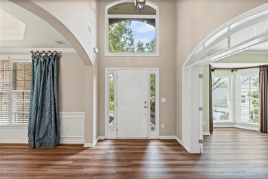 Foyer with wood finished floors, arched walkways, crown molding, a towering ceiling, and a chandelier