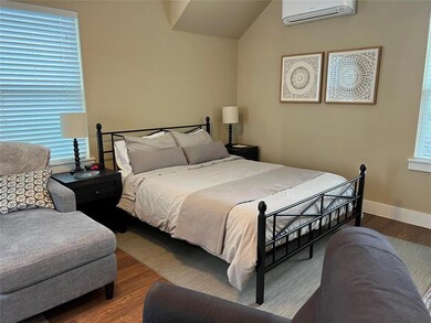 Bedroom with a wall unit AC, wood finished floors