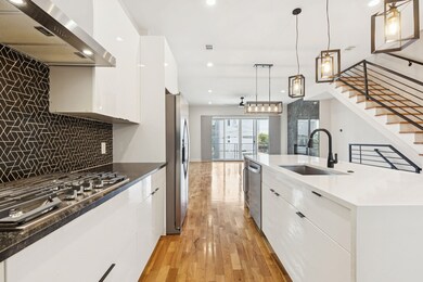 Kitchen featuring white cabinetry, modern cabinets, under cabinet range hood, and recessed lighting