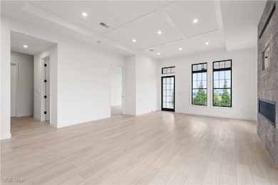 Unfurnished living room with coffered ceiling and light wood-type flooring