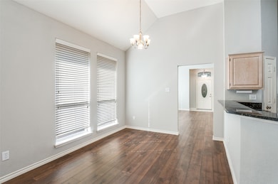 Unfurnished dining area with dark wood-style flooring, a chandelier, and high vaulted ceiling