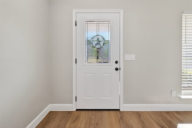 Step inside to a bright and airy entryway, showcasing a beautiful front door with a decorative glass star insert, wood-look flooring, and neutral wall tones.