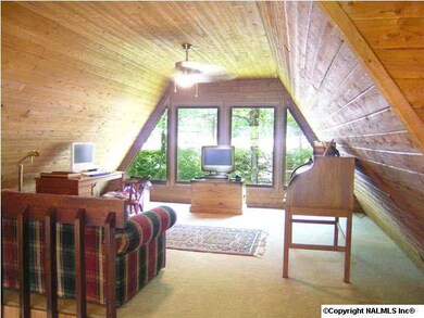 Loft at top of stairs has wood lined walls and fabulous wall of windows to let the sunlight flood the great living space.
