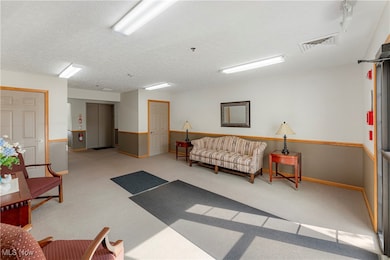 Common area entrance featuring a textured ceiling, stairs, & elevator to upper floors.