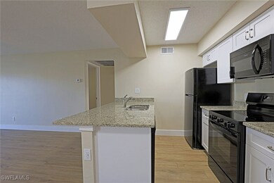 Kitchen featuring visible vents, a sink, light woo