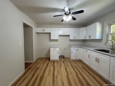 Kitchen featuring light wood-type flooring, white cabinets, and ceiling fan