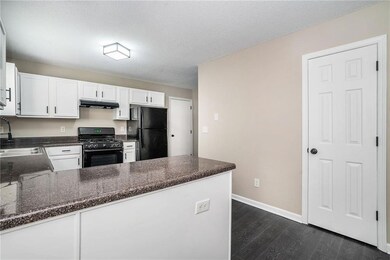 Kitchen with black appliances, white cabinets, dar