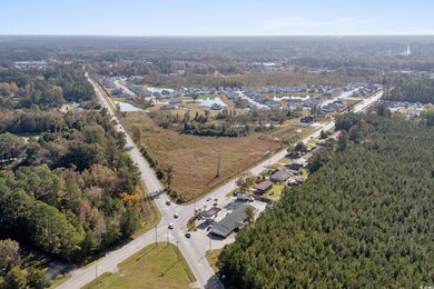 Aerial view of property and surrounding area featuring a forest and nearby suburban area