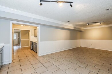 Spare room with track lighting, a wainscoted wall, ornamental molding, a textured ceiling, and light tile patterned flooring