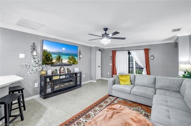 Living area with crown molding, ceiling fan, a glass covered fireplace, light tile patterned floors, and arched walkways