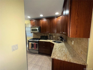 Kitchen featuring backsplash, stainless steel appliances, light tile patterned floors, light stone counters, and recessed lighting