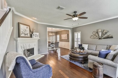 Inviting Living room welcomes guests and family, complete with hand scraped wood floors, crown moulding, and cast stone fireplace.