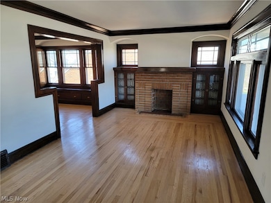 Unfurnished living room featuring ornamental molding, light hardwood / wood-style floors, and a brick fireplace