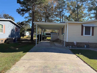 View of vehicle parking with a lawn and a carport