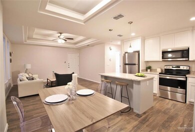 Dining space with a tray ceiling, dark wood-type flooring, recessed lighting, baseboards, and a ceiling fan