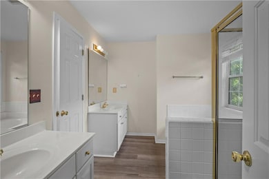 Bathroom with two vanities, wood finished floors, and a tub to relax in