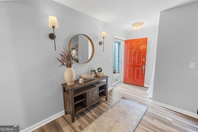 Foyer featuring wood finished floors, a textured ceiling, and baseboards
