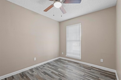 Empty room featuring a textured ceiling, wood fini
