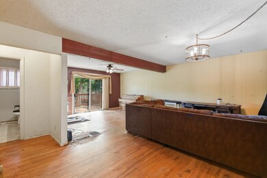 Living room featuring light wood-style flooring, a textured ceiling, ceiling fan, and beamed ceiling